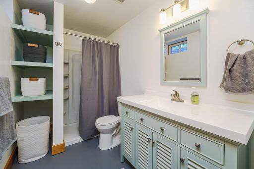 The 3/4 bathroom just underwent a FULL RENOVATION and includes a NEW shower surround, a charming SOLID WOOD shuttered vanity with a cultured marble top, NEW lighting, linen storage, toilet, trim and paint! Open shelves on the wall match the vanity.