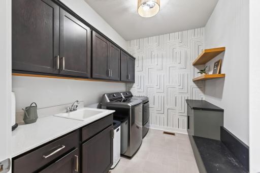 Main-level laundry w/laundry tub which has quartz sink and additional storage added