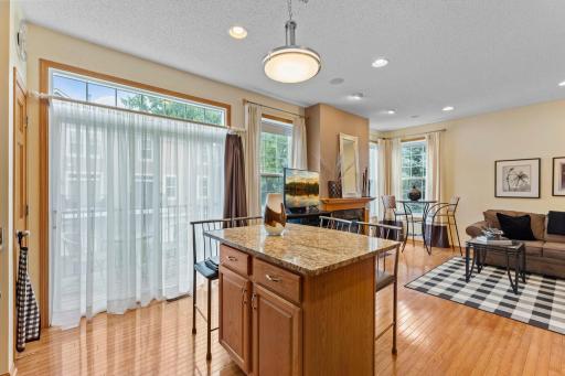 Bright, open-concept living space featuring beautiful hardwood floors, a spacious kitchen island, cozy fireplace, and an abundance of natural light.