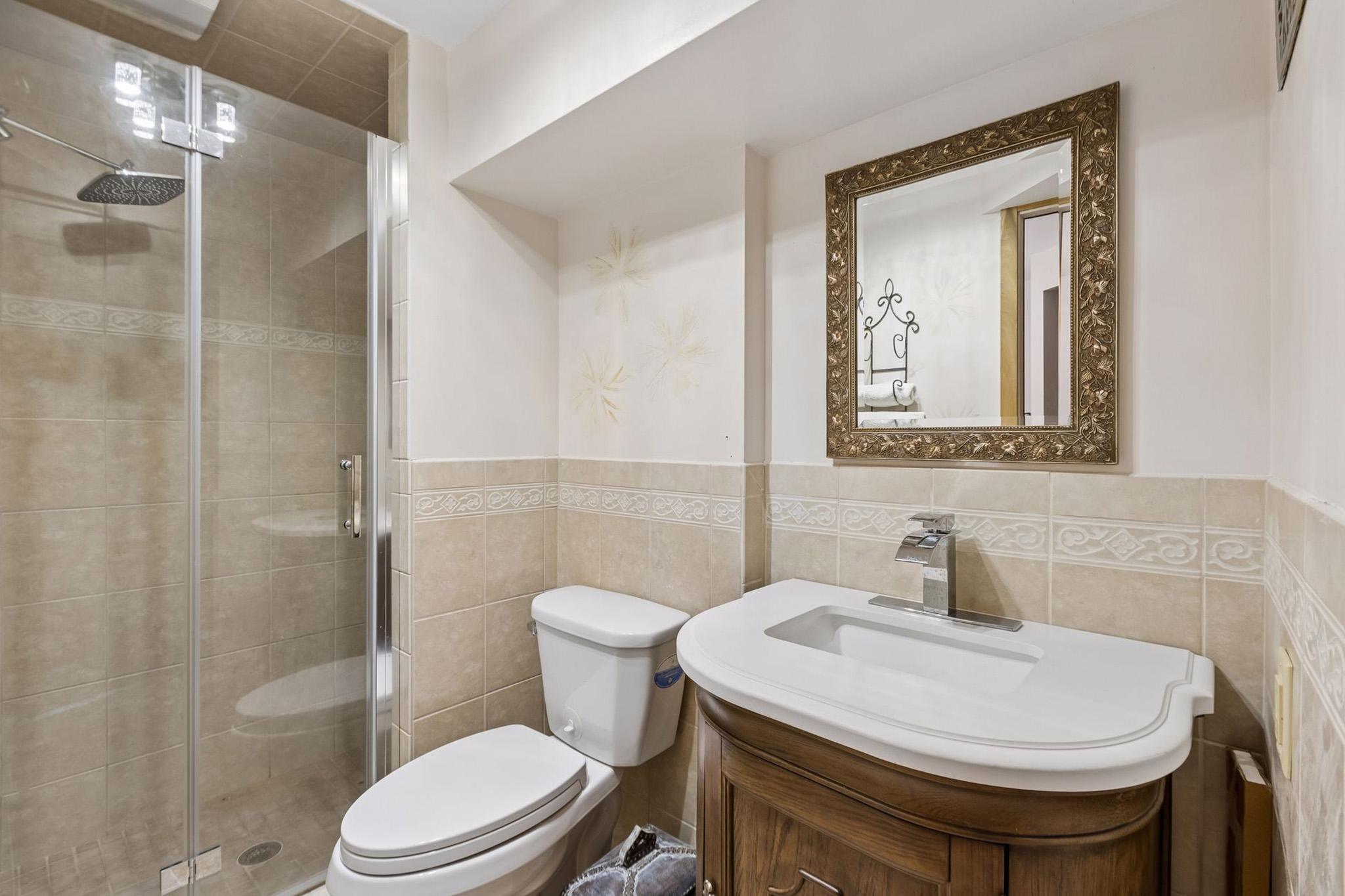 27. Updated 3rd bath featuring floor-to-ceiling walk-in shower, new vanity and faucet, and contemporary light fixture.jpg