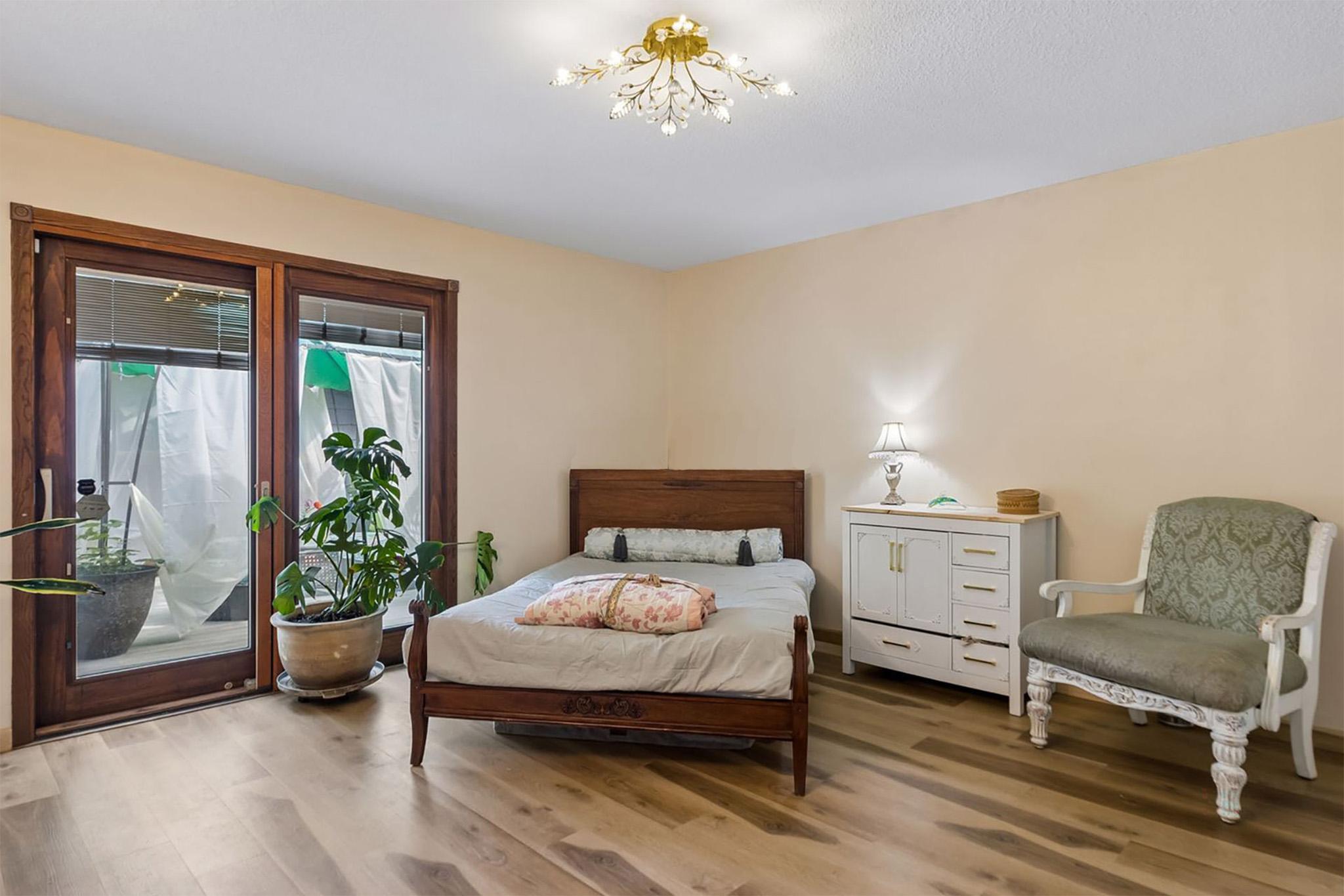 15. Spacious primary bedroom retreat, featuring a sparkling crystal light fixture and direct door access to the private backyard deck.jpg