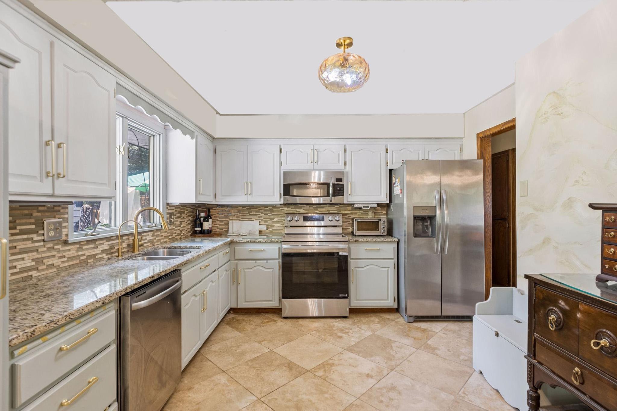 11. Bright kitchen featuring white top and ice mint bottom cabinets cabinets, gold accents, marble tops, tile backsplash.jpg
