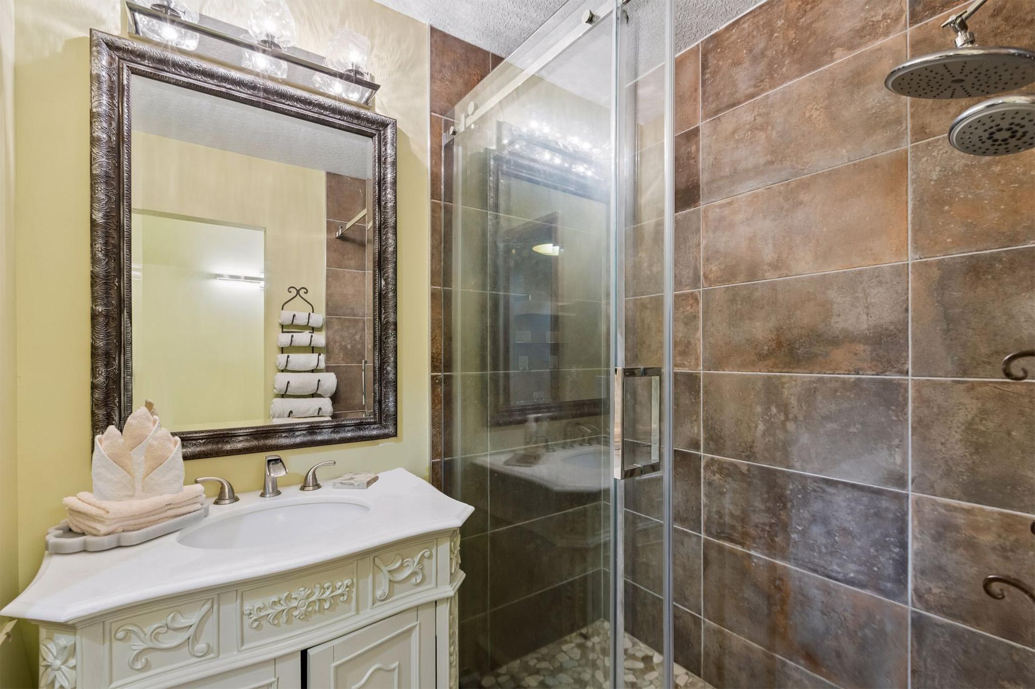 21. Bathroom 2 featuring full walk-in tile shower, exquisite carved vanity with quartz countertop, and unique light fixture.jpg