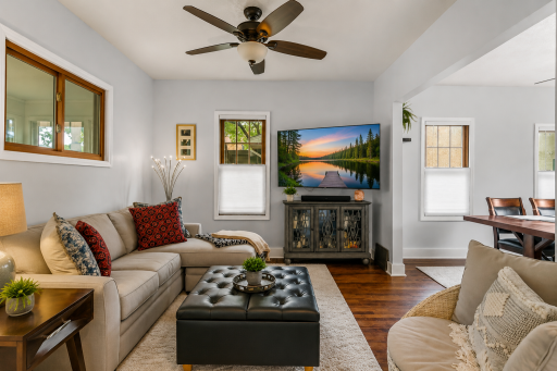 Bright & Inviting Main-Level Living Room! Comfortable gathering space featuring beautiful hardwood floors, abundant natural light and an open flow into the adjoining dining area. AI-enhanced TV image.