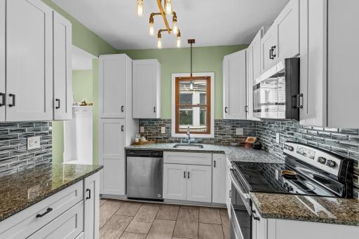 Beautifully Updated Kitchen! Bright and functional with crisp white cabinetry, granite countertops, stainless-steel appliances, stylish tile backsplash and updated lighting.