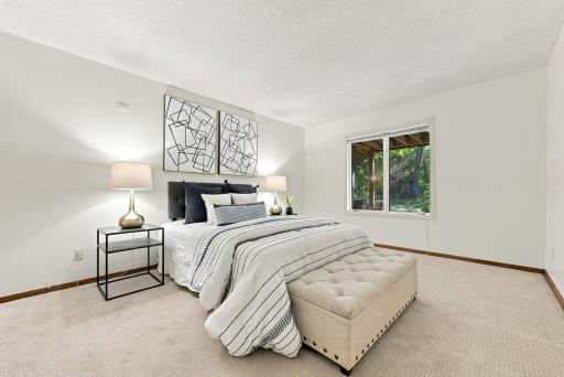 Another generously sized bedroom with windows overlooking the surrounding greenery.