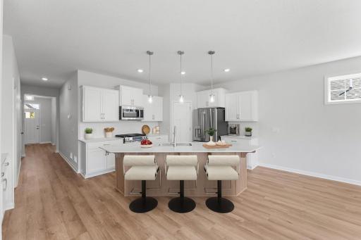 The inviting kitchen comes nicely appointed with upgraded appliances, walk-in pantry, quartz countertops with subway tile backsplash, and large island providing additional seating, storage and prep space.