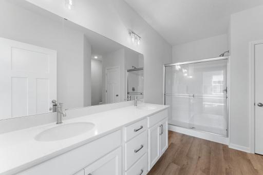 The primary on-suite features soothing design details, an oversized vanity, walk-in shower, and large linen closet.