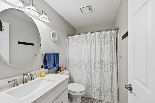The full, tiled bathroom features a newer hard surfaced vanity.