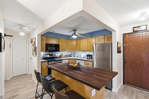 This shot features the eat-in kitchen with the entrance on the right, and the hallway to the bedroom and bathroom on the left. The kitchen also features under-counter lighting.