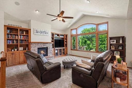 Vaulted great room with gas fireplace, stone surround, and custom built-ins sized for a large TV.