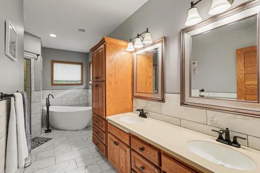 Primary bath with dual sinks, ceramic tile, and a freestanding soaking tub.