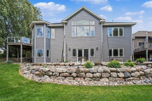 Back exterior showing the walkout lower level, deck, and landscaped yard with Peachtree Willows along the east side.