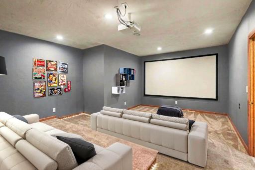 Wide angle of the lower level theater room showing full seating capacity and screen setup. (virtually staged)