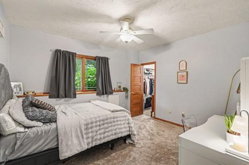 Second lower level bedroom with walk-in closet, carpet, ceiling fan, and backyard views.