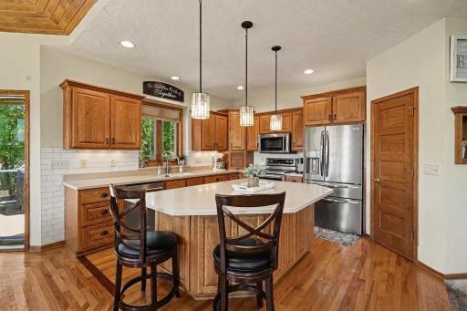 Custom kitchen with stainless appliances, hard surface countertops, tiled backsplash, and a pantry off the prep area.