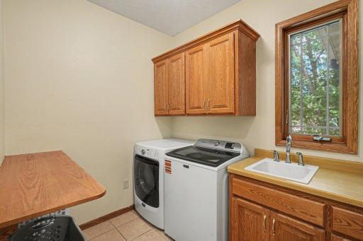 Main level laundry room with cabinetry, a folding shelf, and a sink.
