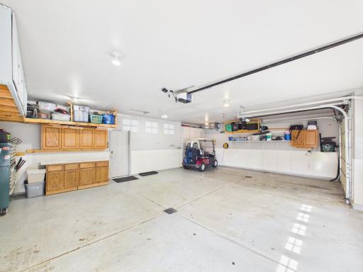 Spacious heated 3-car garage with built-in cabinets, wall storage, floor drains, and direct interior access.