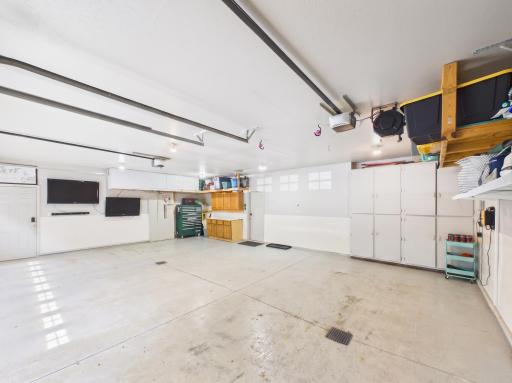 Heated 3-car garage with built-in storage, utility cabinets, floor drains, and room for vehicles, gear, and projects.