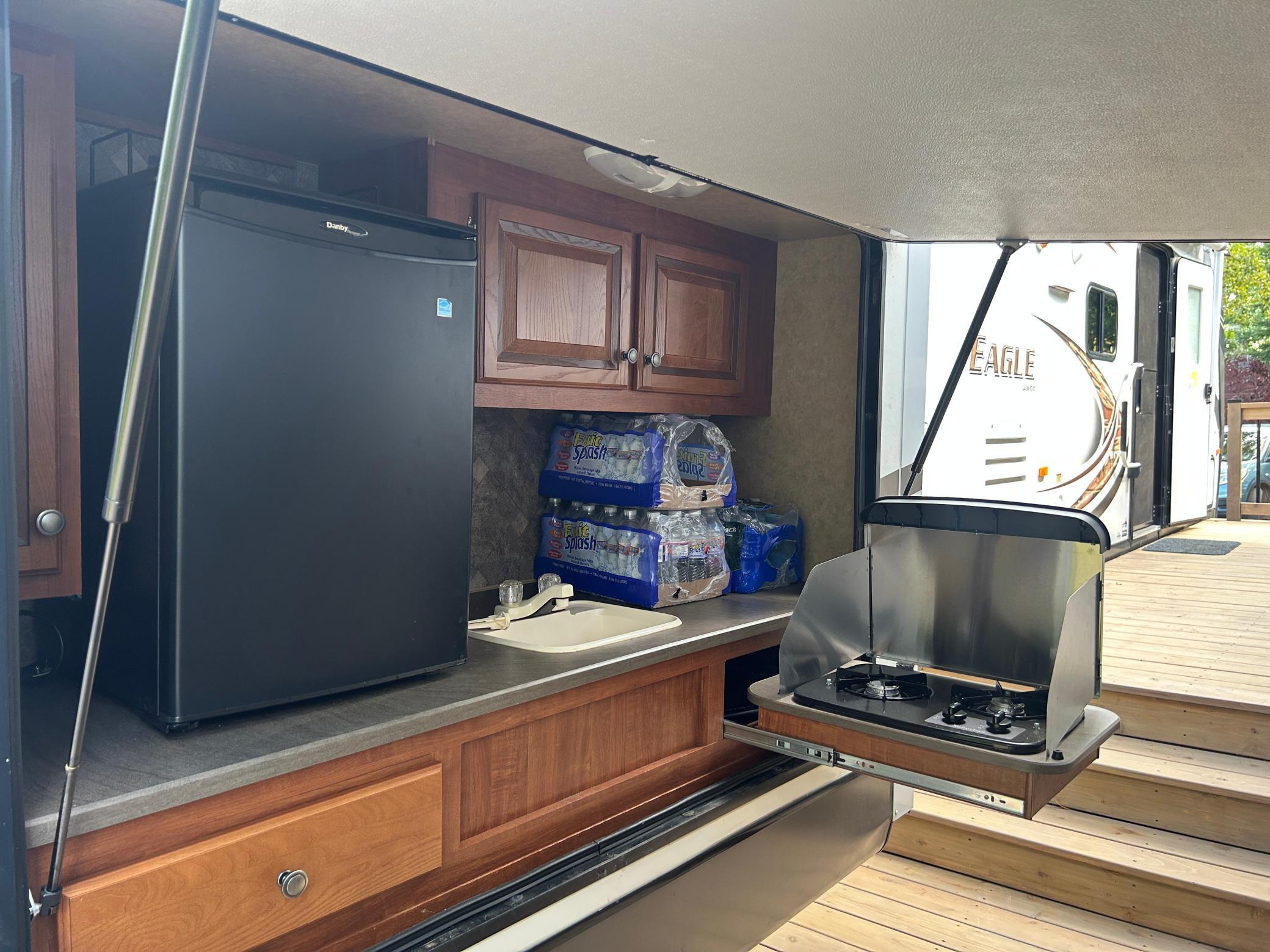Outdoor kitchen comes complete with refrigerator, stove and sink with water!