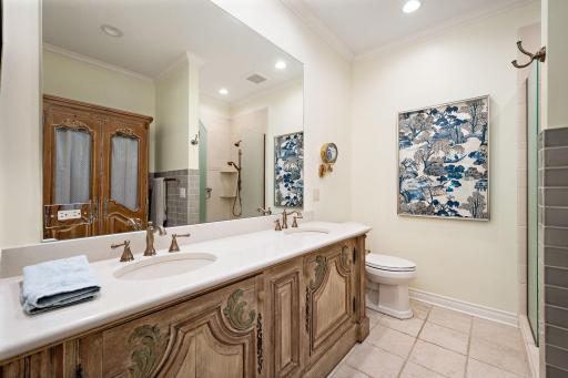 Updated primary bathroom with dual-sink vanity, heated marble floors and updated tile shower.