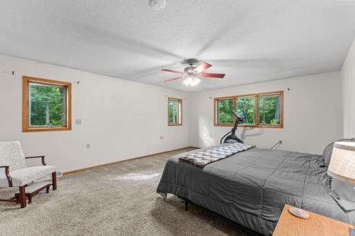 Large primary bedroom with multiple windows and plenty of space for a king bed, furniture and dressers