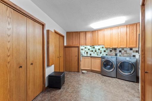 The spacious laundry room offers abundant cabinets and closets for storage