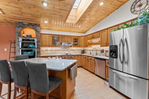 Expansive size kitchen with a center island, stainless appliances and a wall-mount double oven with a brick surround offering a bit of Italian flare