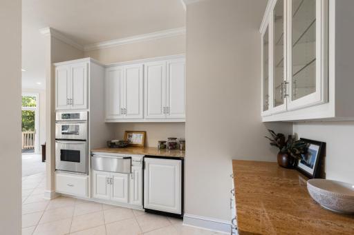Convenient kitchen serving area with additional cabinetry, counter space, beverage refrigerator, and double ovensâperfect for entertaining and extra storage.