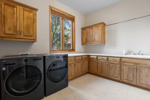 Spacious main-level laundry room featuring abundant cabinetry, generous counter space, and a convenient utility sink.