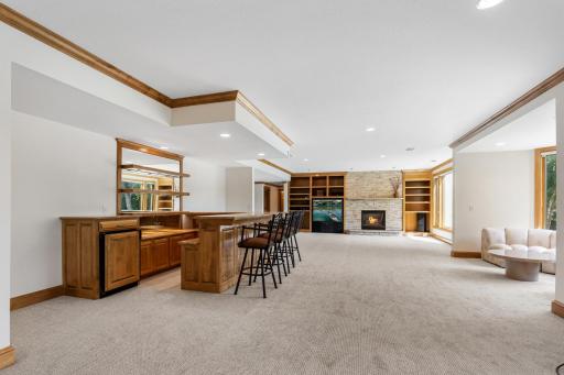 Another view of the expansive lower-level family room showcasing the wet bar, fireplace, custom built-ins, and incredible space for entertaining family and friends.