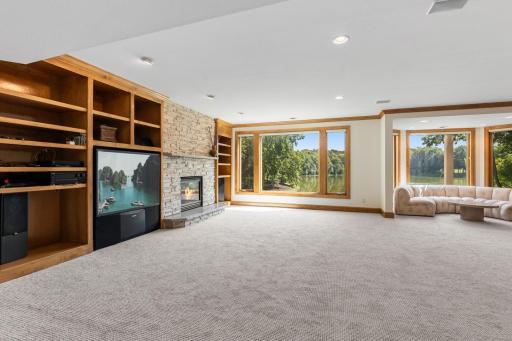 Impressive 48' x 27' walkout lower-level family room featuring brand-new carpet, a cozy fireplace, custom built-ins, and an abundance of space for entertaining, relaxing, and recreation.