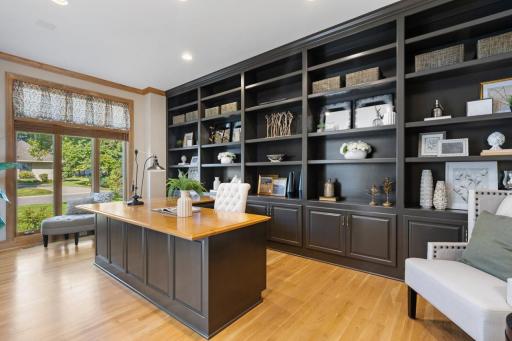 Private main-level office featuring impressive floor-to-ceiling custom built-ins, a spacious executive desk, and French doorsâan ideal work-from-home setting.