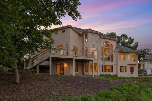 Beautiful rear exterior showcasing the homeâs expansive deck, walkout lower level, and walls of windows designed to capture the peaceful Turtle Pond setting.
