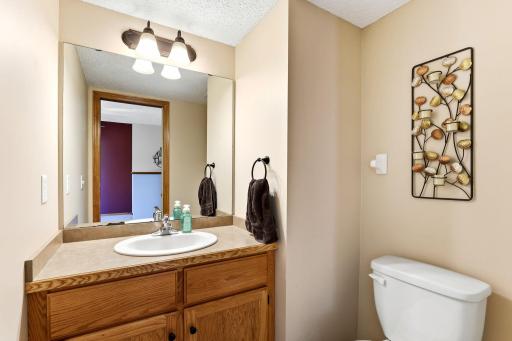 Convenient main-level half bath featuring a spacious vanity, large mirror, and warm wood cabinetry.