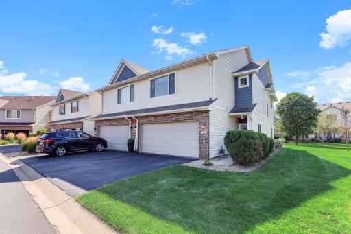 Beautiful end-unit townhome featuring a charming combination of vinyl and brick siding and attractive curb appeal. The home offers a spacious two-car garage, well-maintained landscaping, and a generous side yard with mature shrubbery.