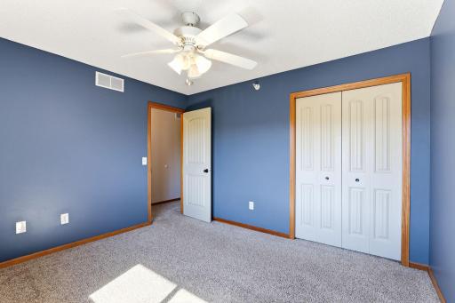 Another view of the upper-level bedroom highlighting plush carpeting, ceiling fan, and generous double-door closet.
