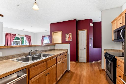 Spacious kitchen with abundant cabinetry, generous counter space, double sink, hardwood floors, pantry, and an open view into the living area.