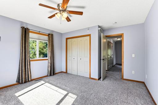 Another view of the bright upper-level bedroom showcasing plush carpeting, ceiling fan, generous closet space, and natural light.