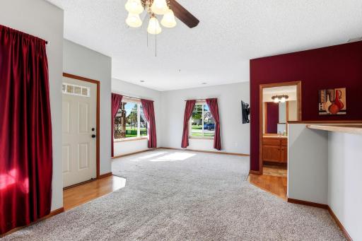 Bright, open living and dining spaces with abundant natural light, plush carpeting, and convenient access to the main-level half bath.