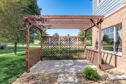 Private patio with pergola and lattice side panels, creating a defined outdoor living space with added privacy and views of the surrounding green space.