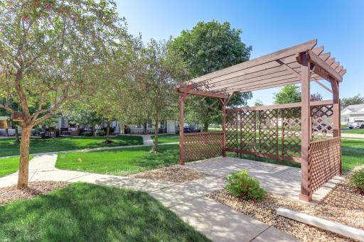 Another view of the patio and pergola, featuring added lattice side panels for enhanced privacy and a peaceful setting surrounded by mature trees and green space.