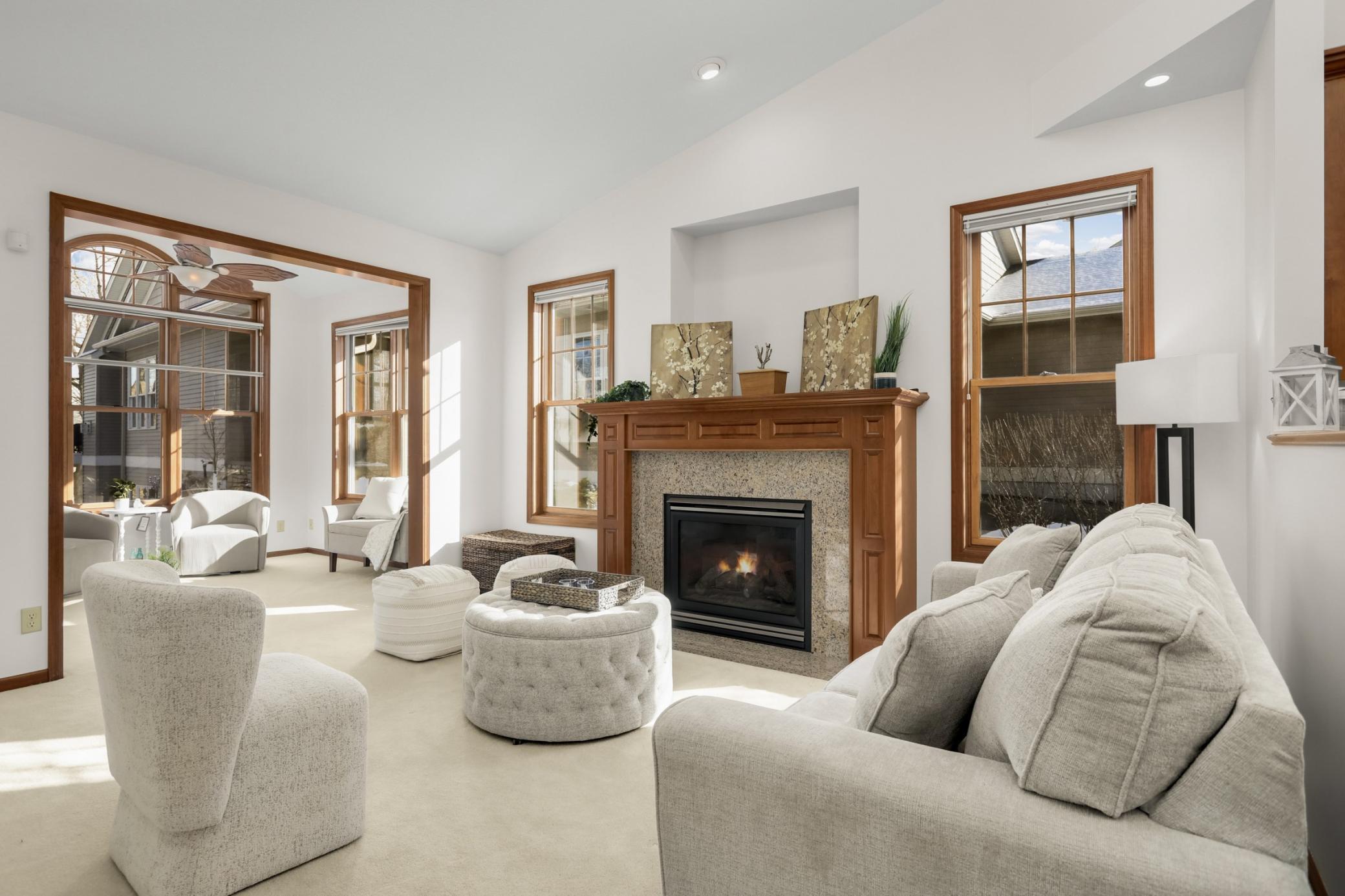 Sun-filled living room with cozy gas fireplace, expansive windows, and vaulted ceilings overlooking the natural setting.
