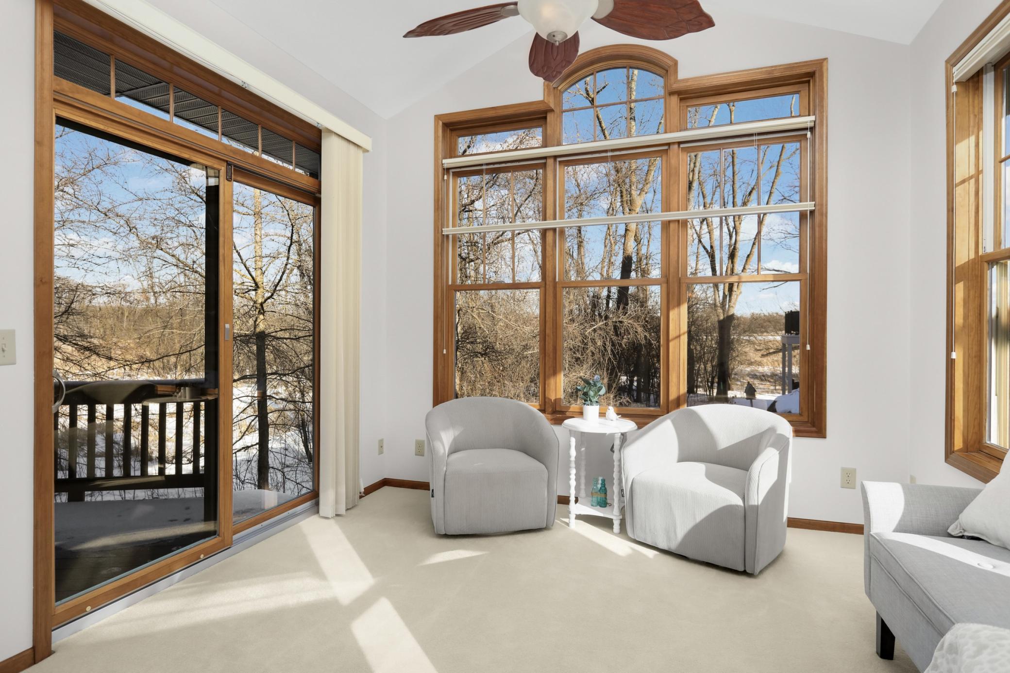 Light-filled sitting area with panoramic windows and deck access—perfect for morning coffee overlooking the water.