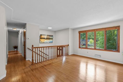 The inviting living room showcases beautiful original hardwood floors, a large front-facing picture window that fills the space with natural light, and peaceful neighborhood views.