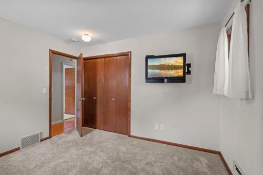 Bedroom two, located right across the hall from bedroom two, offers carpeting, ample closet space, and a mounted TV.