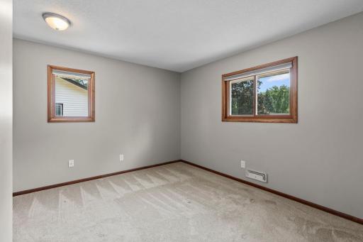 Bedroom one offering carpeting, ample natural light, and a mounted TV.