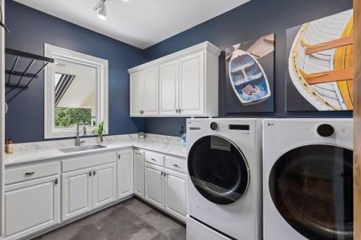 A well-equipped laundry room offers a sink, cabinetry and generous counter space.