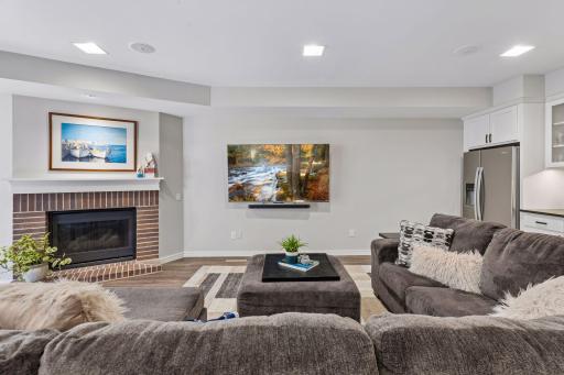The lower-level family room offers comfortable gathering space beside a gas fireplace.