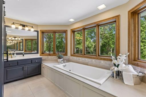 The primary ensuite features a jetted tub surrounded by tranquil treetop views.
